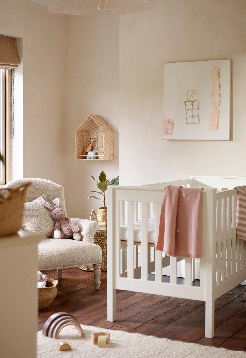 a baby's room with a crib, a chair, a rug and a window