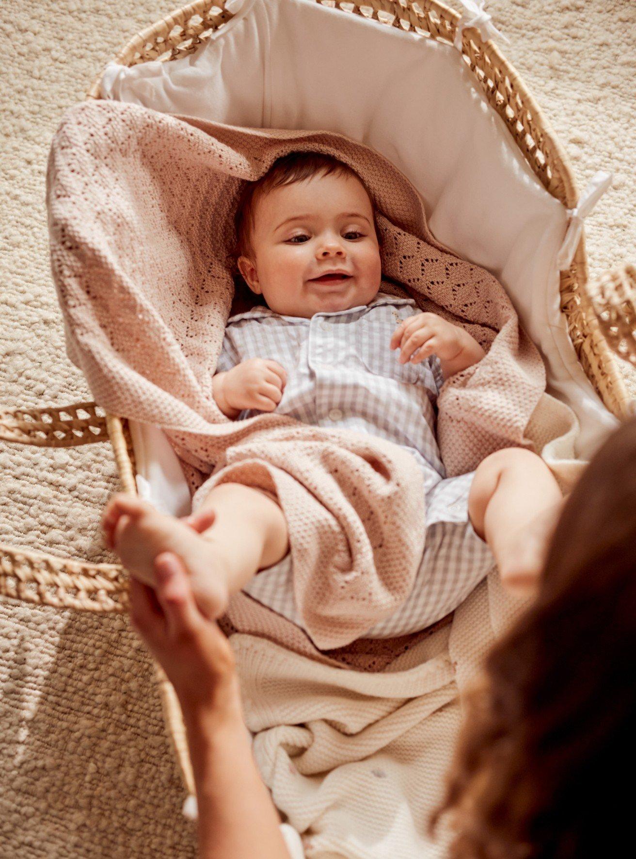 a baby in a basket with a woman reaching for it