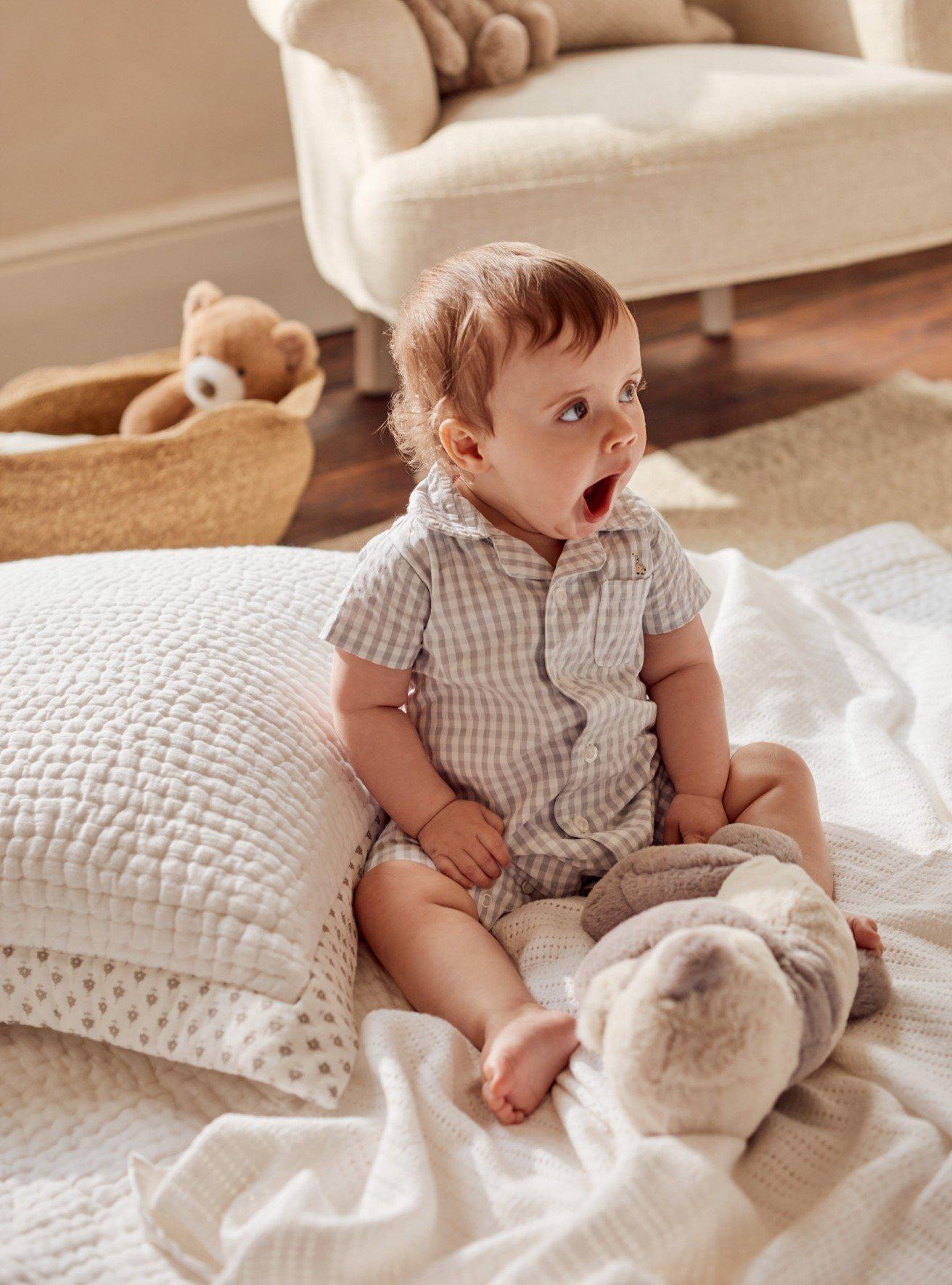 a baby sitting on a bed with a stuffed animal