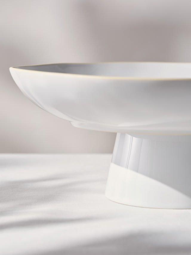 a white bowl sitting on a table with a white background