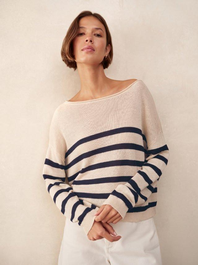 a woman in white pants and a striped sweater posing