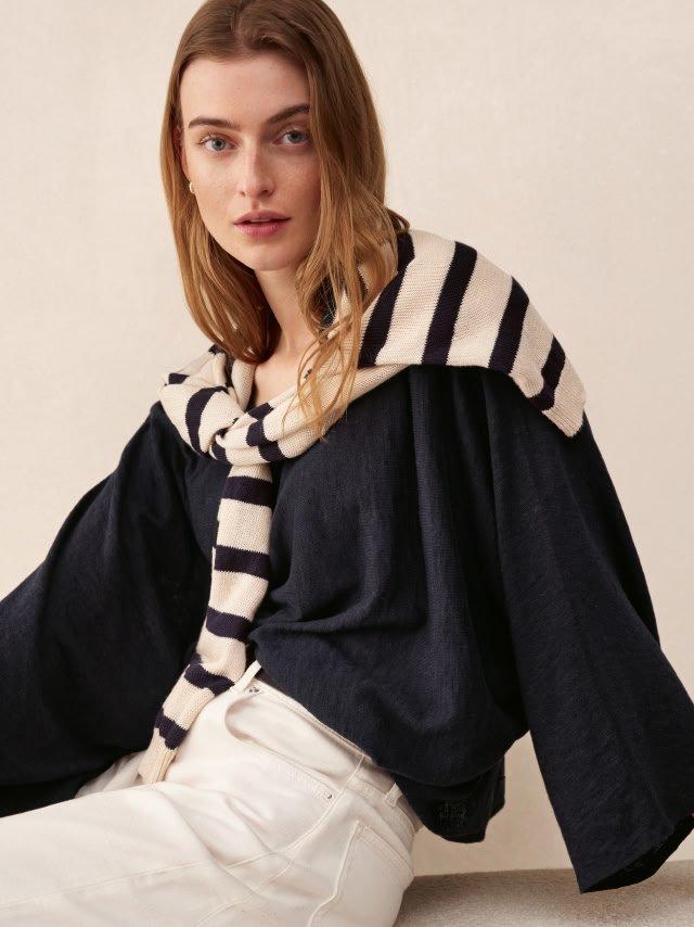 a woman in a black and white striped shirt and white pants