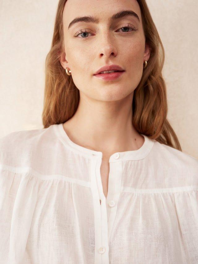 a woman with long brown hair wearing a white blouse