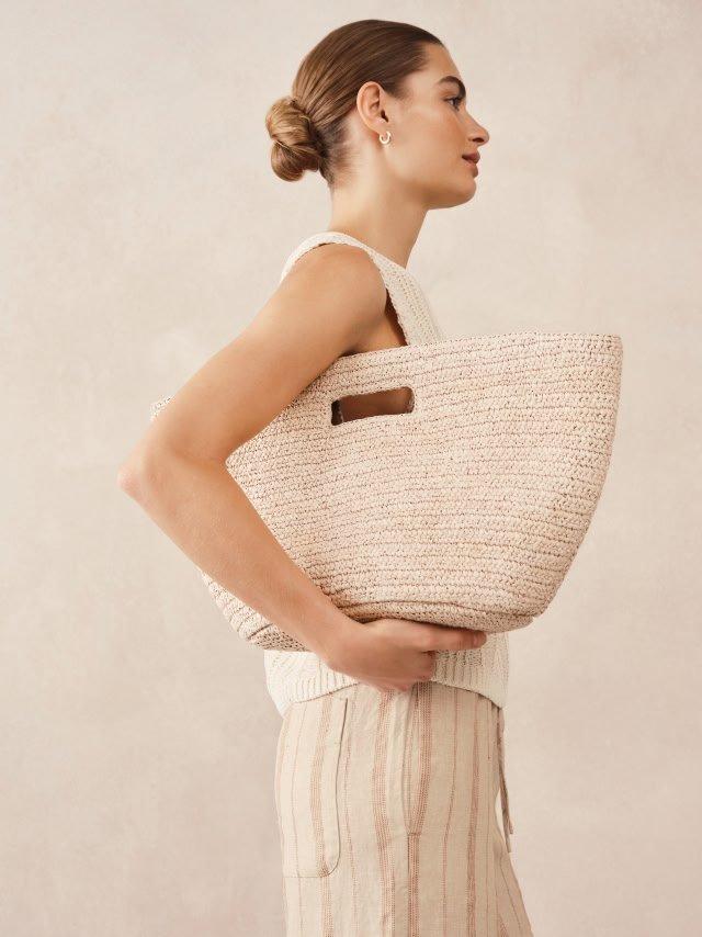 a woman is holding a large tote bag