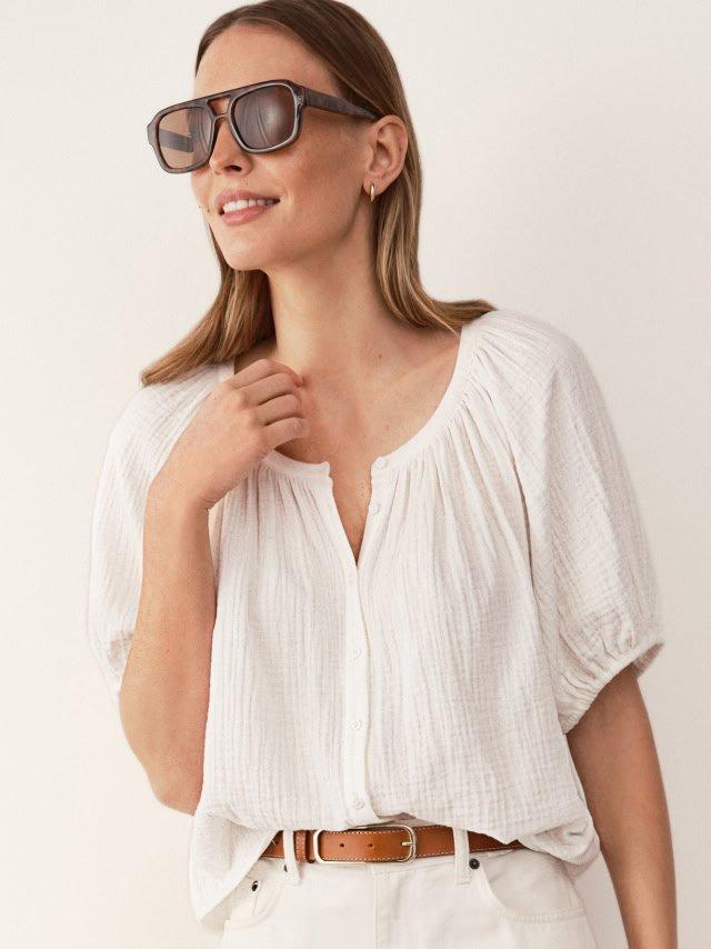 a woman in white shirt and sunglasses posing for a picture