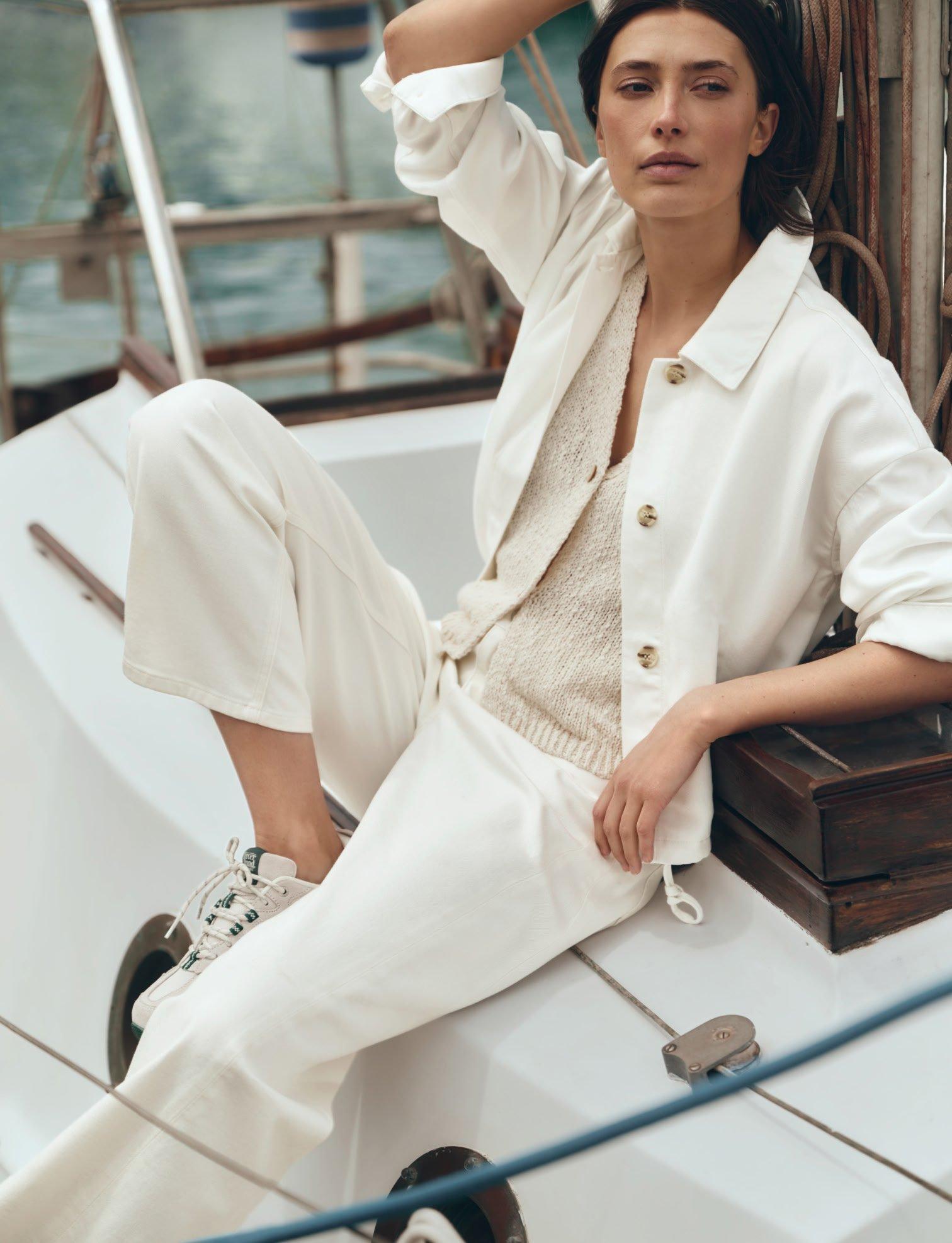 a woman in white sitting on a boat in the water