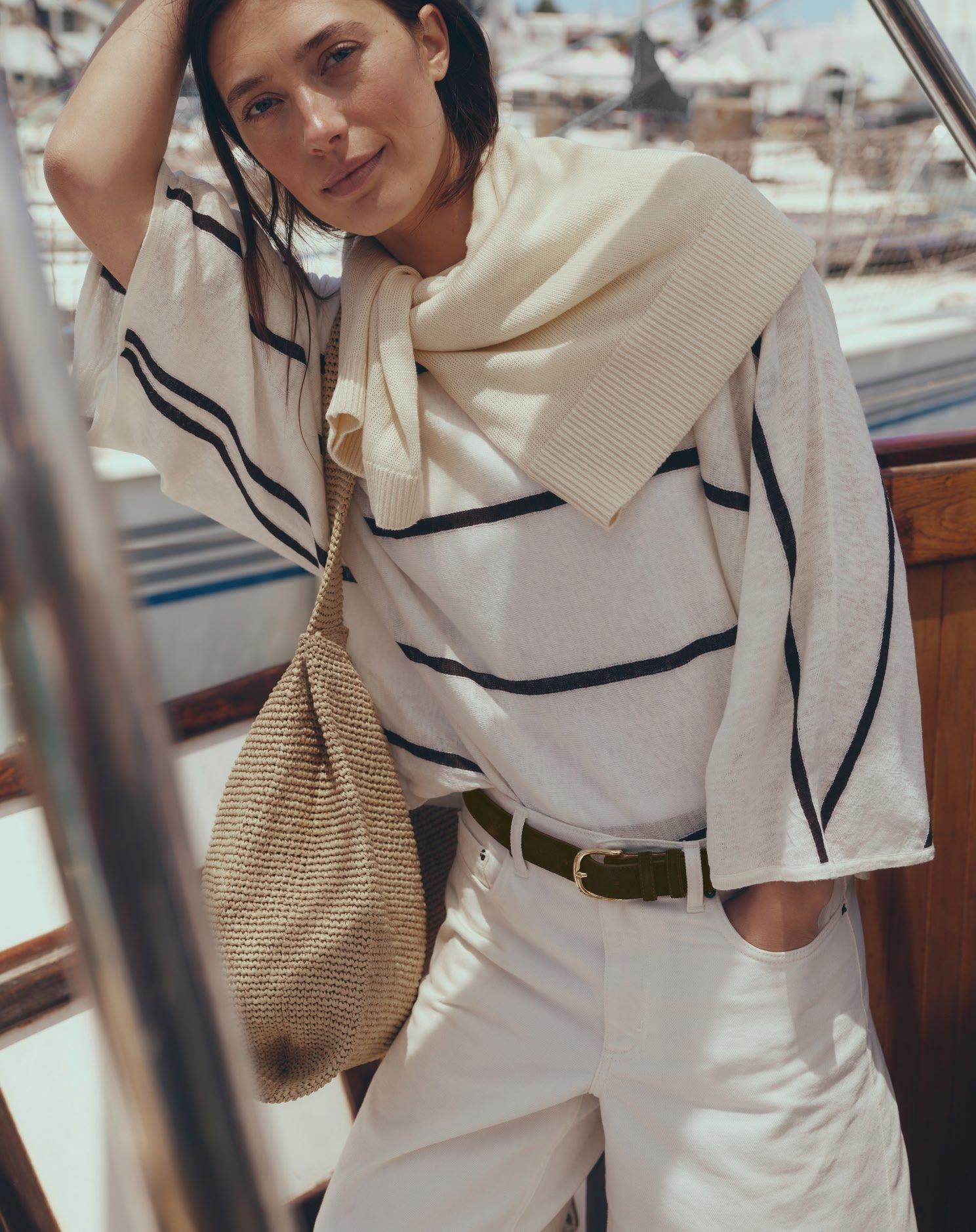 a woman in a white shirt and scarf posing on a boat