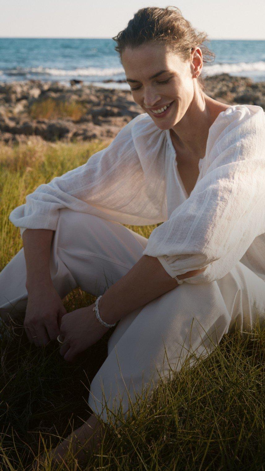 a woman in a white shirt sitting on the beach