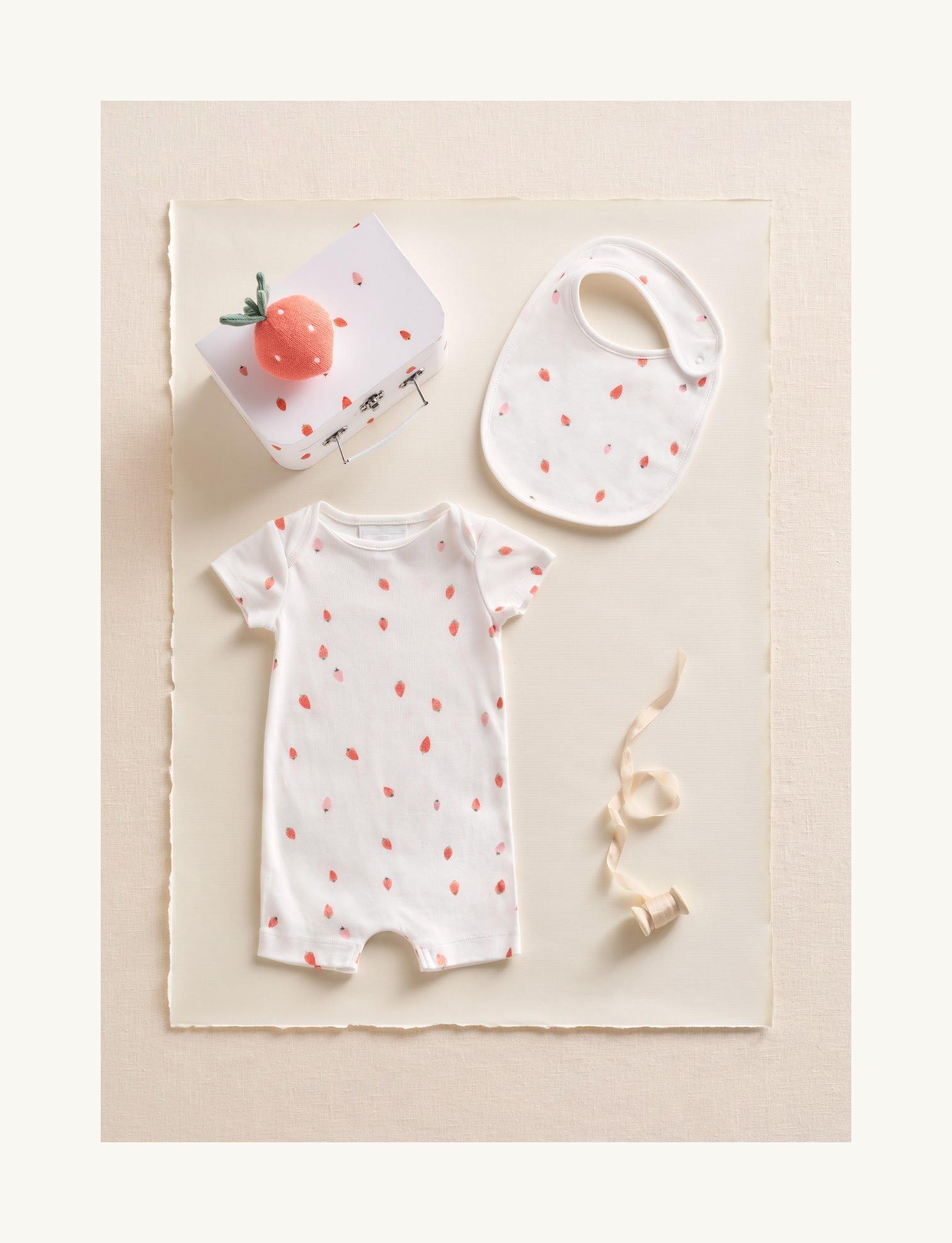 a baby's outfit with a bib and a strawberry