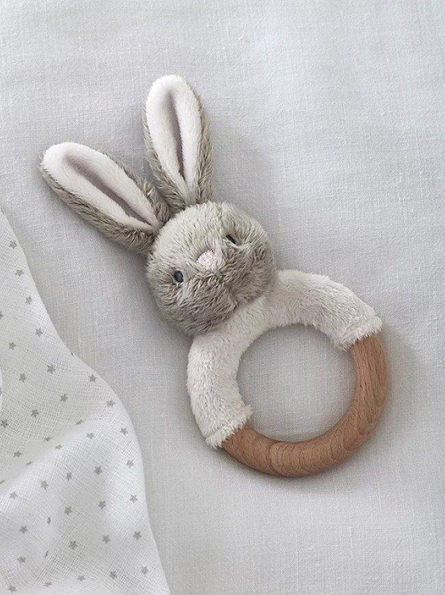a stuffed rabbit toy laying on a white sheet next to a pillow