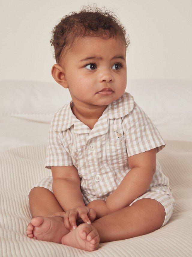 a baby sitting on a bed with a white sheet