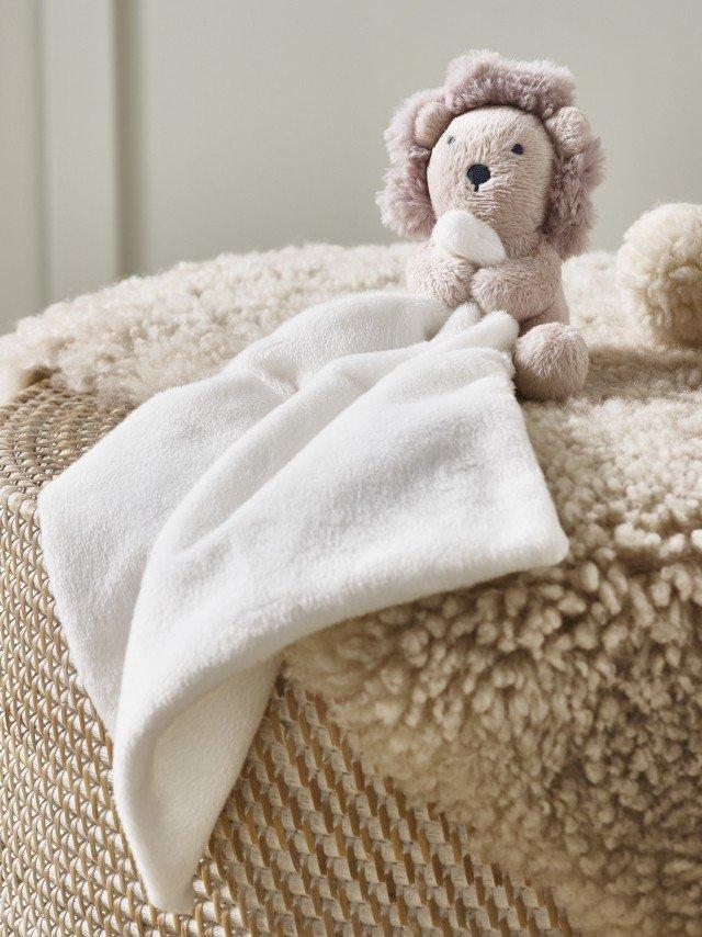 a stuffed animal sitting on top of a stool with a blanket