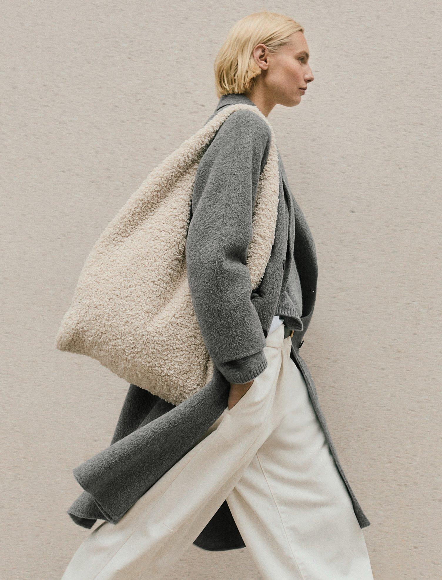 a woman walking down the street with a large bag on her shoulder