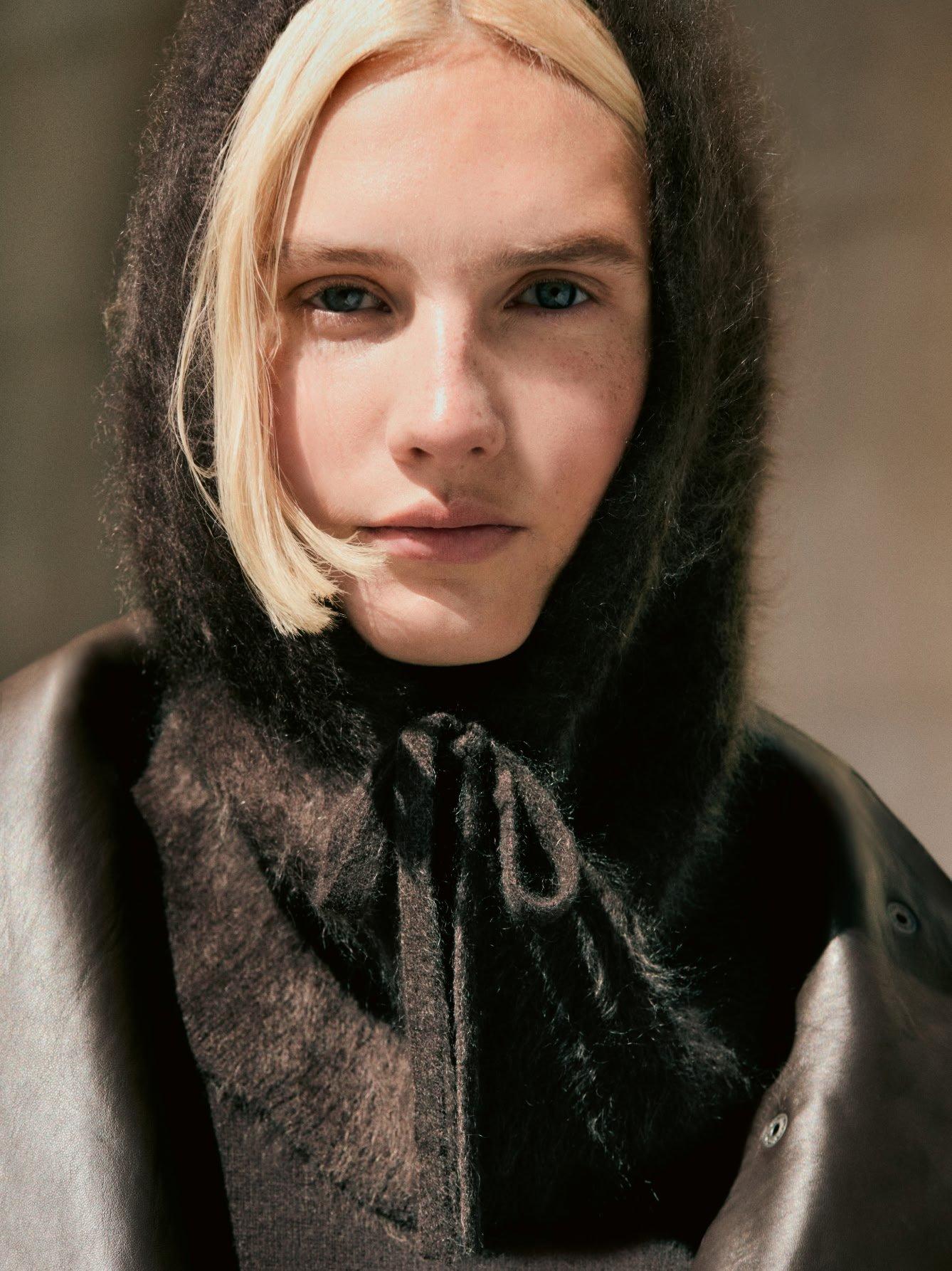 a woman with a hood on her head and a black jacket