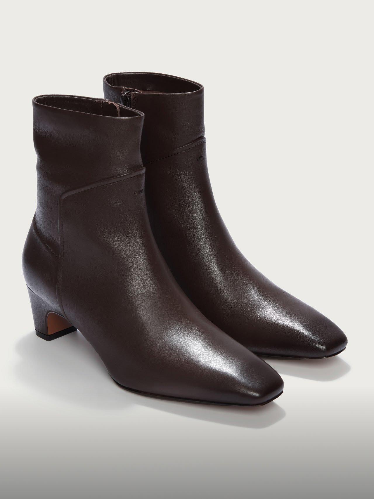 a pair of brown leather ankle boots on a white surface