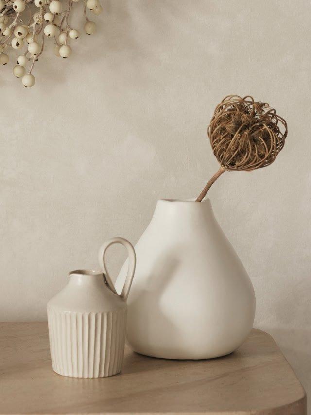 a vase and pitcher on a table with a flower in it