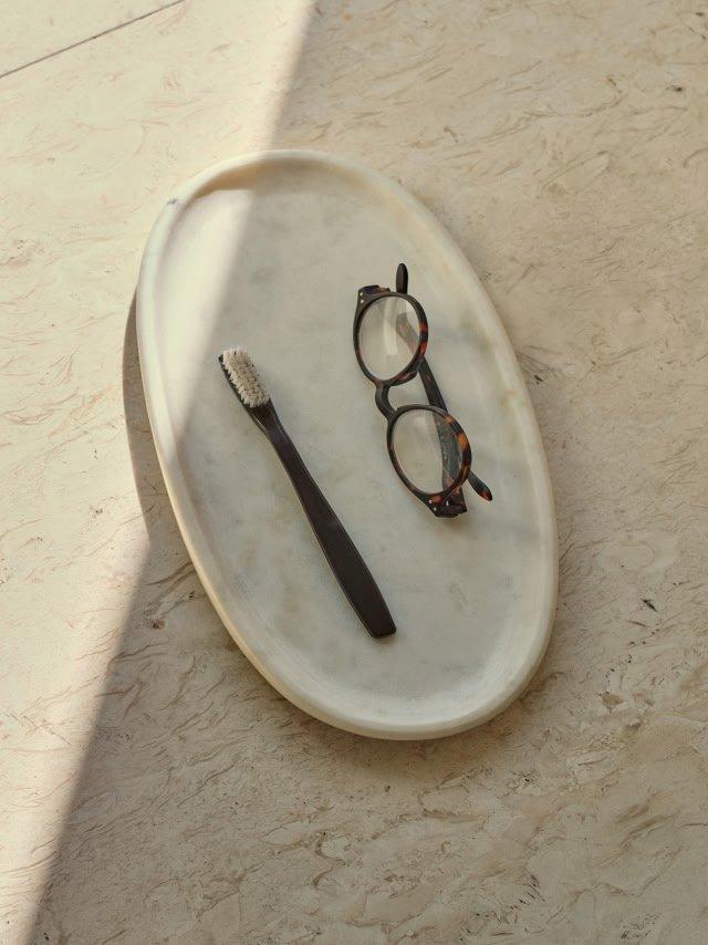 a toothbrush and glasses on a white plate on a table