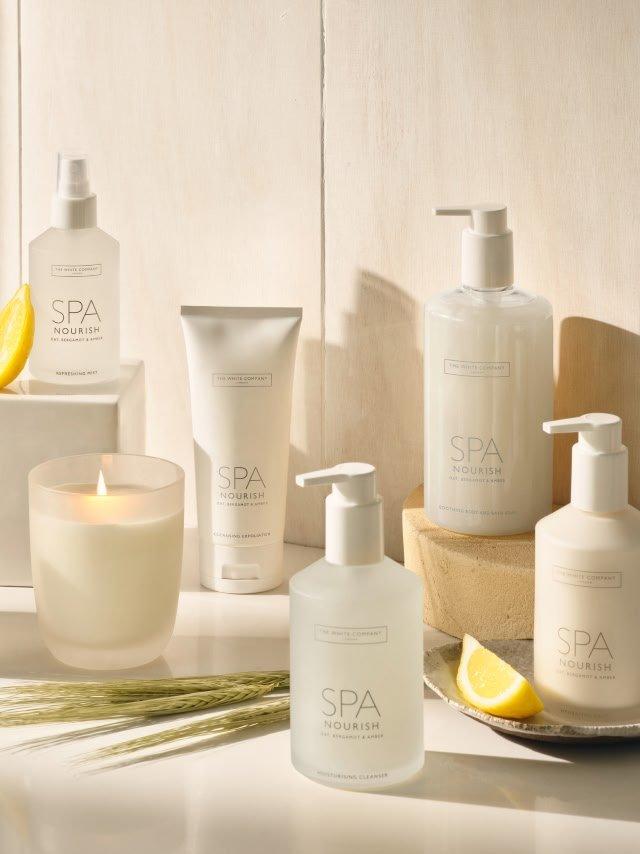 a white counter with a bottle of lotion, a candle, and a lemon
