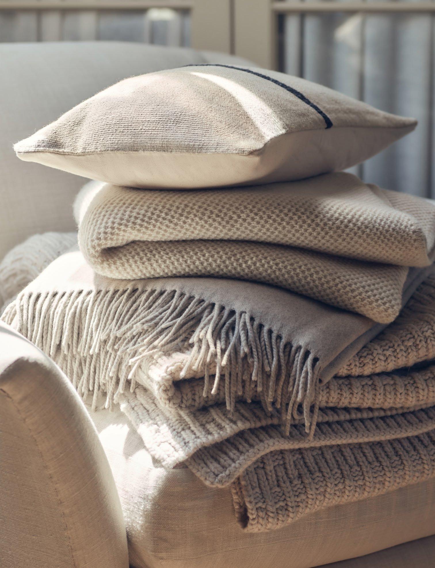 a stack of blankets and pillows on a chair in a living room