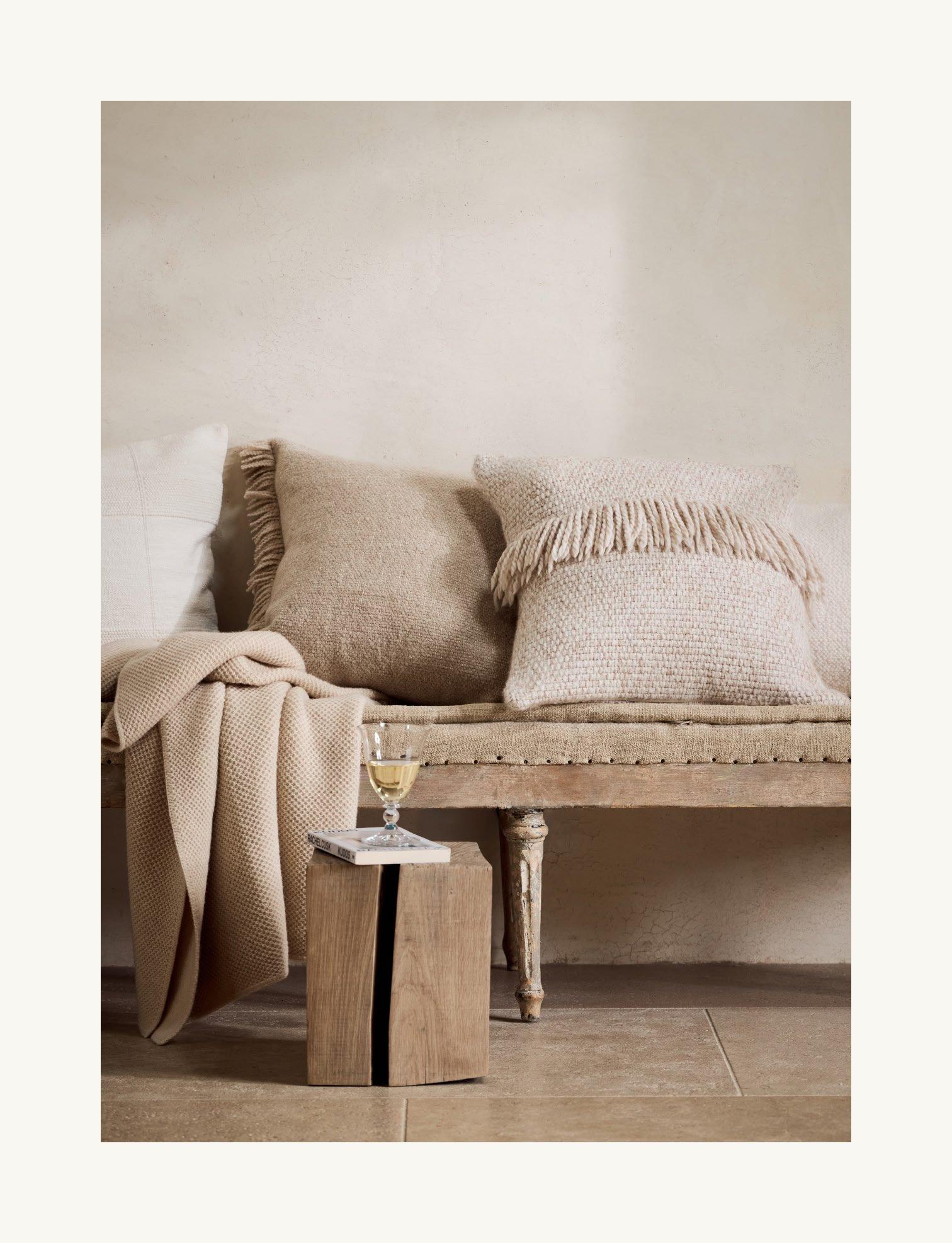 a couch with pillows and a wine glass on it next to a wall
