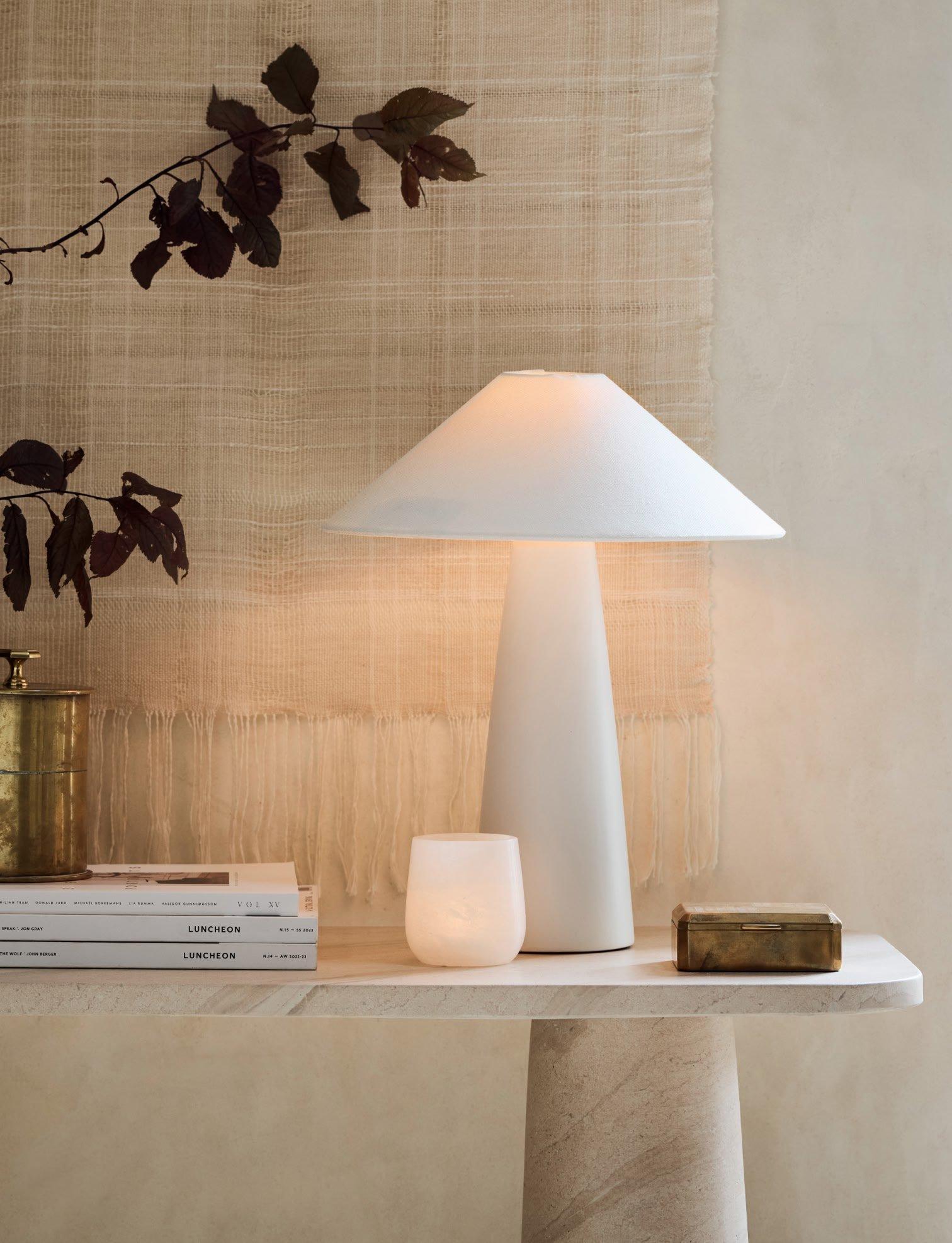 a table with a lamp, books, and a candle on it