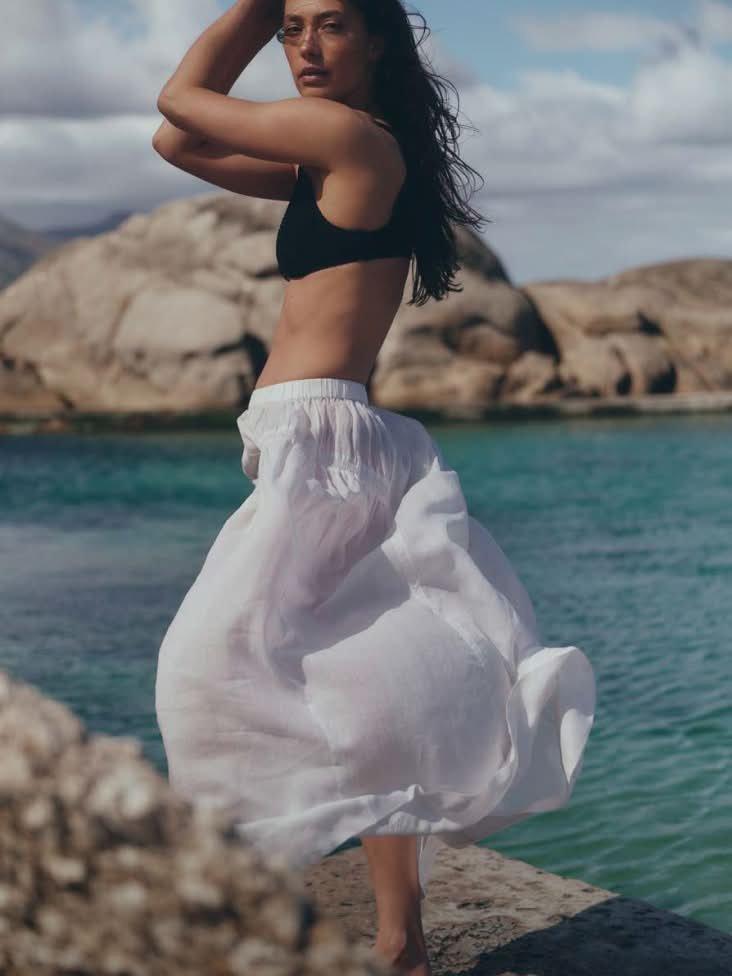 a woman in a black and white bikini standing on a rock