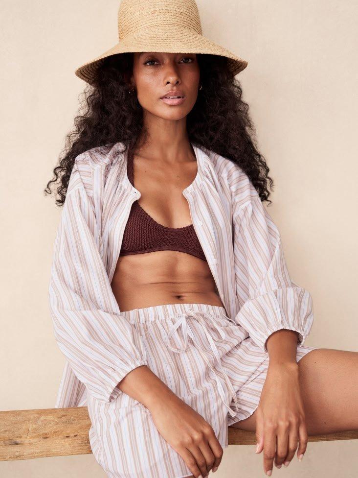 a woman in a hat and shorts sitting on a bench