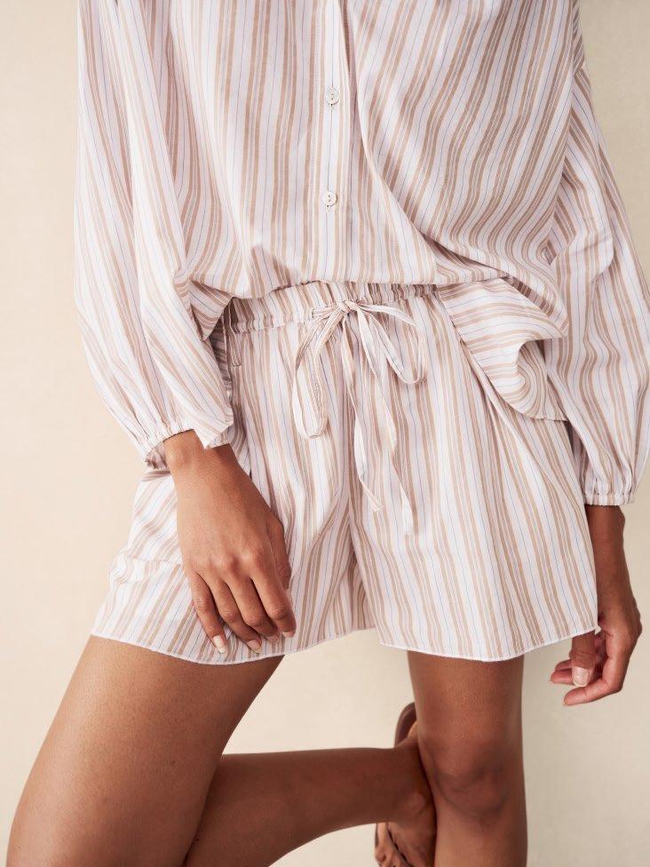 a woman in a striped pajama shorts and sandals