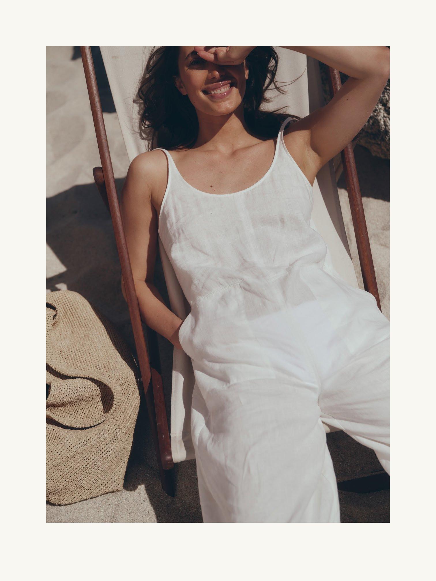 a woman in white jumpsuit sitting on a chair with sunglasses on
