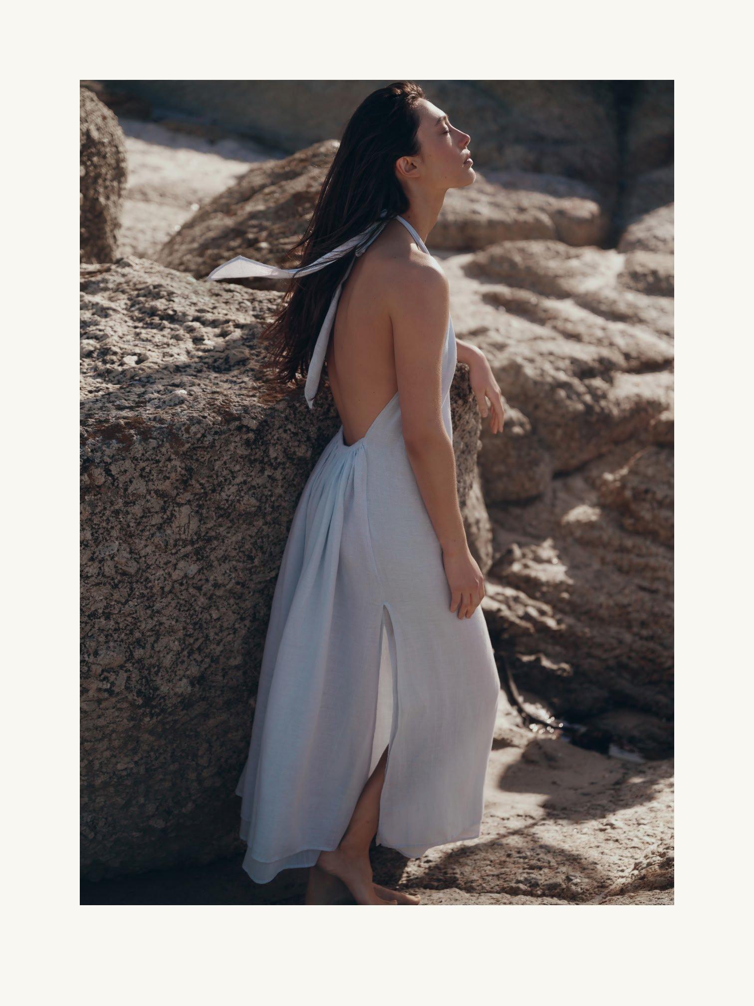a woman in a white dress standing next to a wall