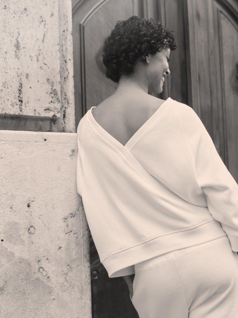 a woman in white standing by a door with her back to the camera