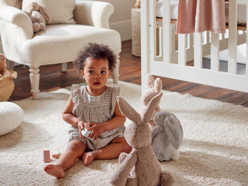 a baby sitting on a white rug with stuffed animals