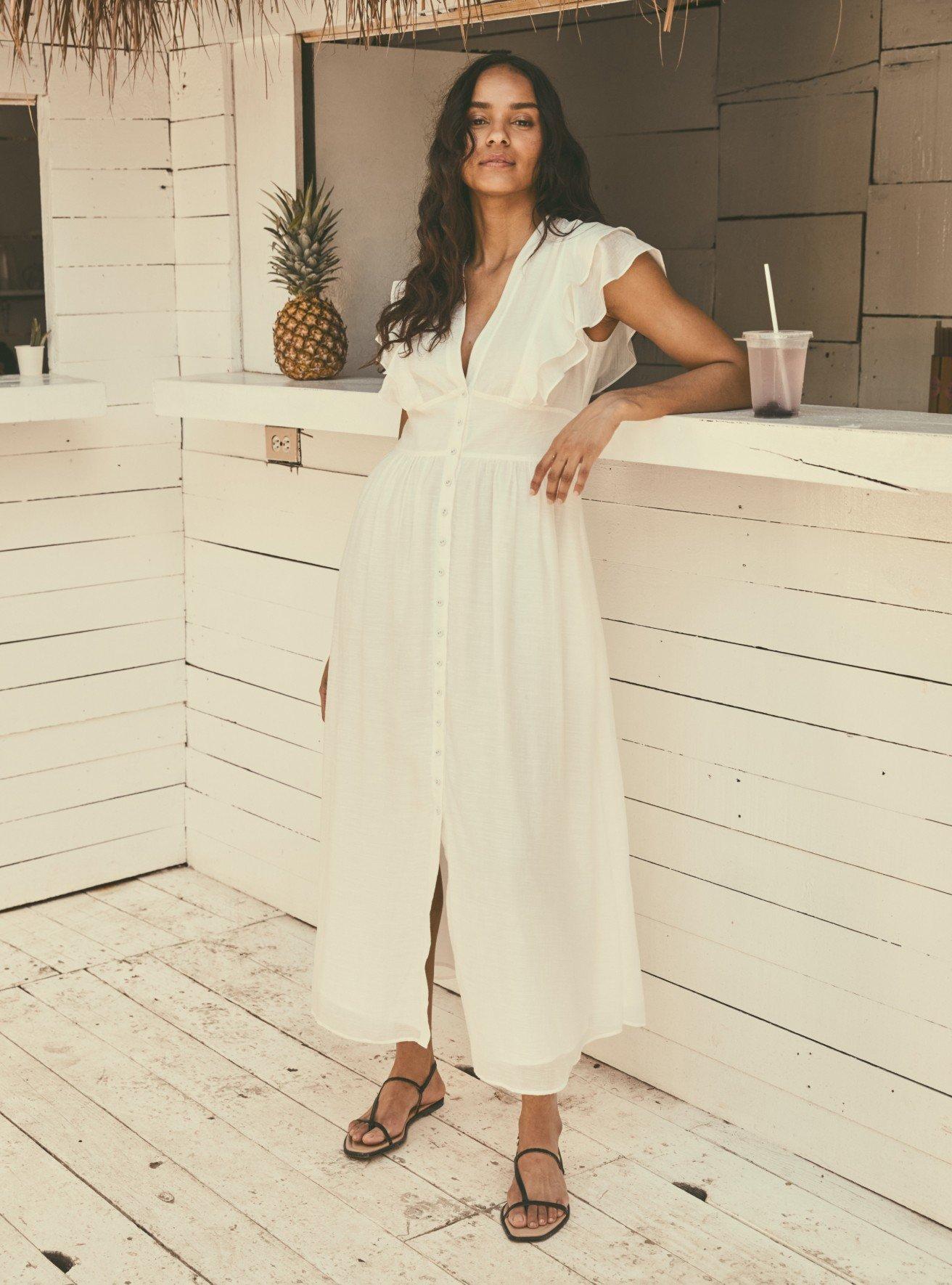 a woman in a white dress standing on a set of stairs