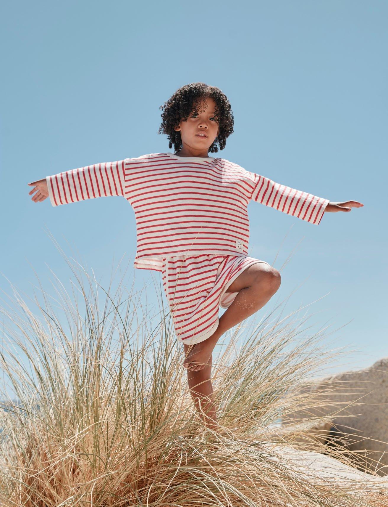 a young girl standing on top of a tall grassy hill