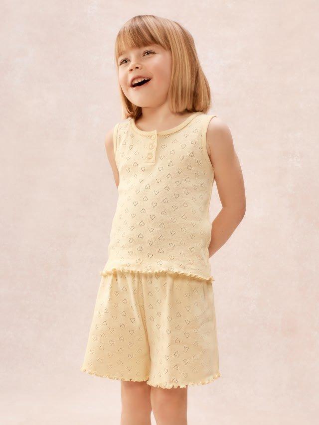 a little girl in yellow pajamas standing on a white floor