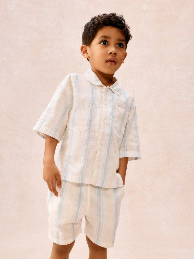 a young boy in a white shirt and shorts standing on a white floor