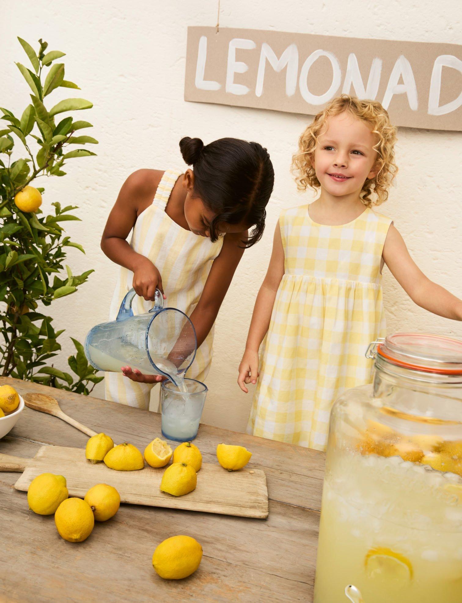two little girls are pouring lemonade into a pitcher