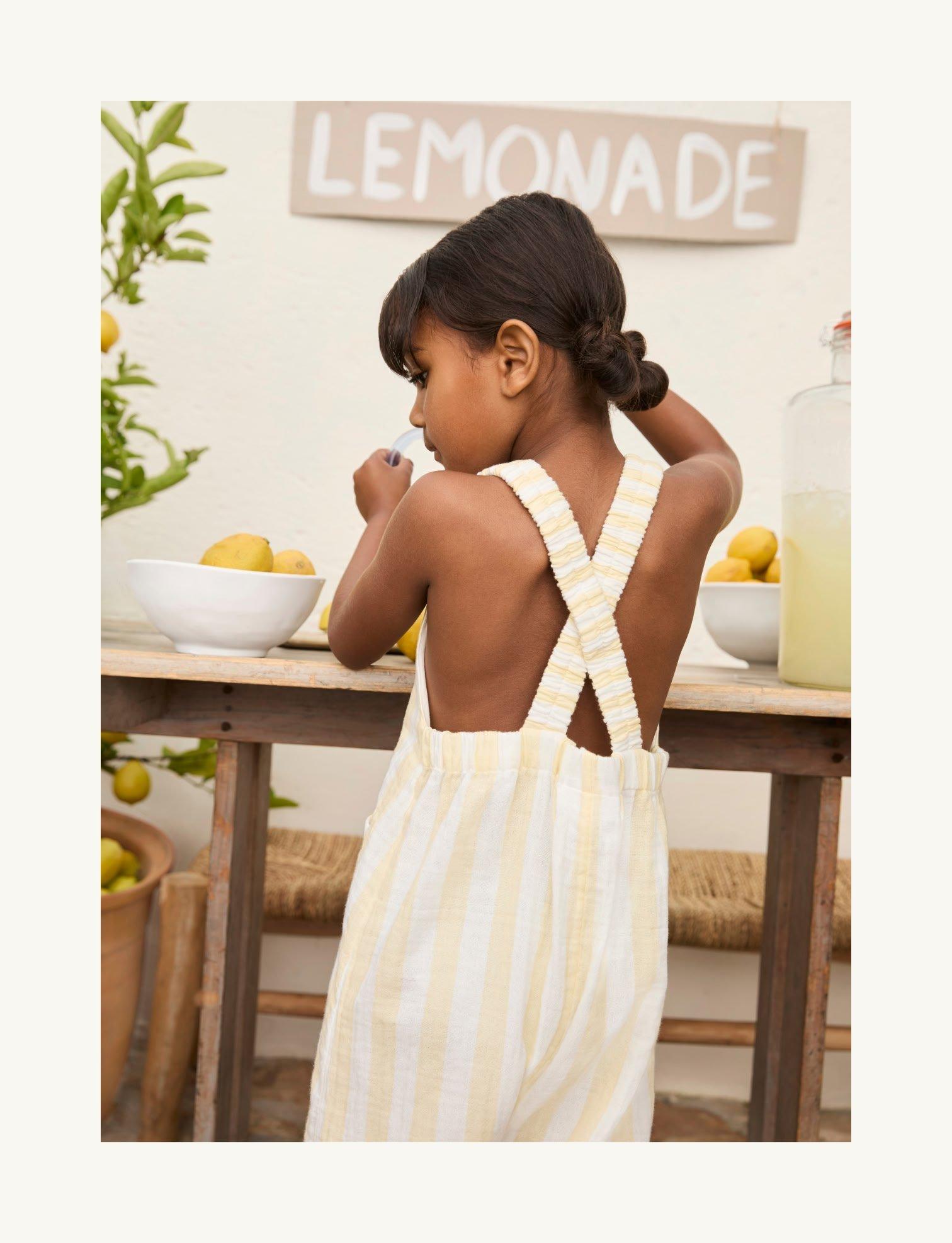 a little girl in a yellow dress is standing at a table