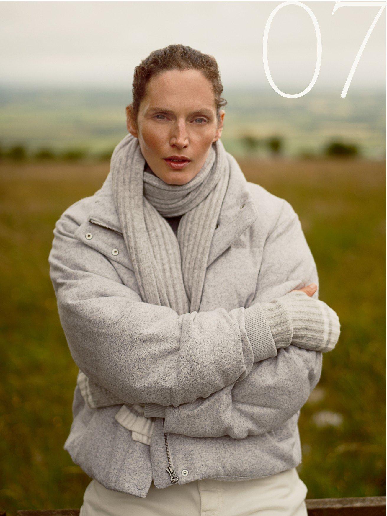 a woman in a white coat standing in a field