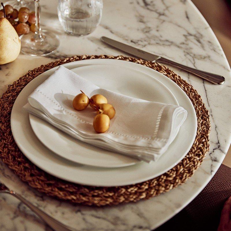 a white plate with a white napkin on it sitting on a marble table