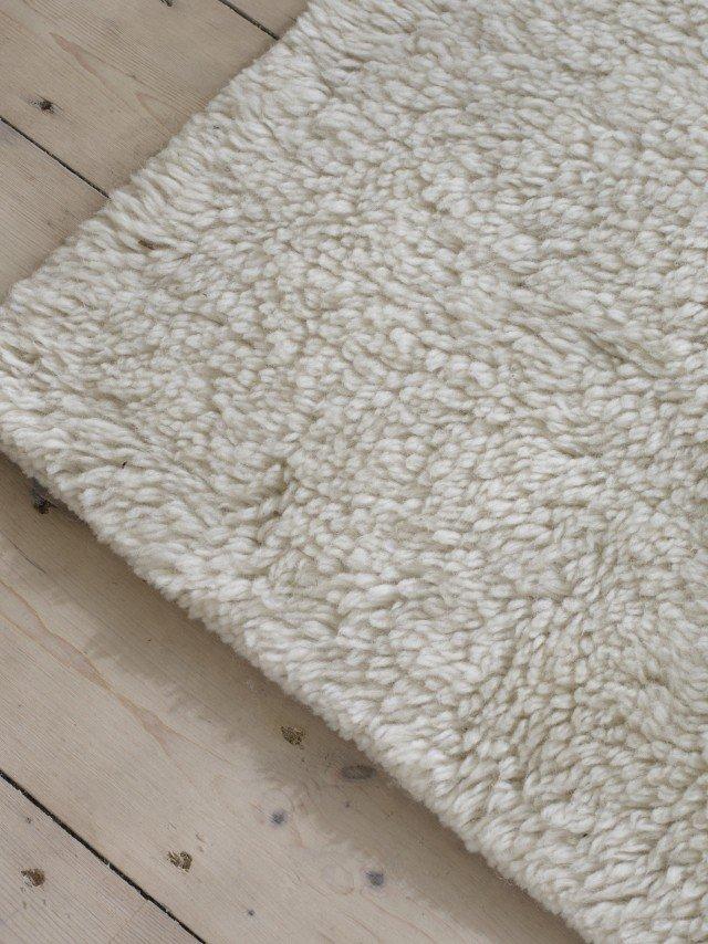 a white rug with a yellow dot on it on a wooden floor