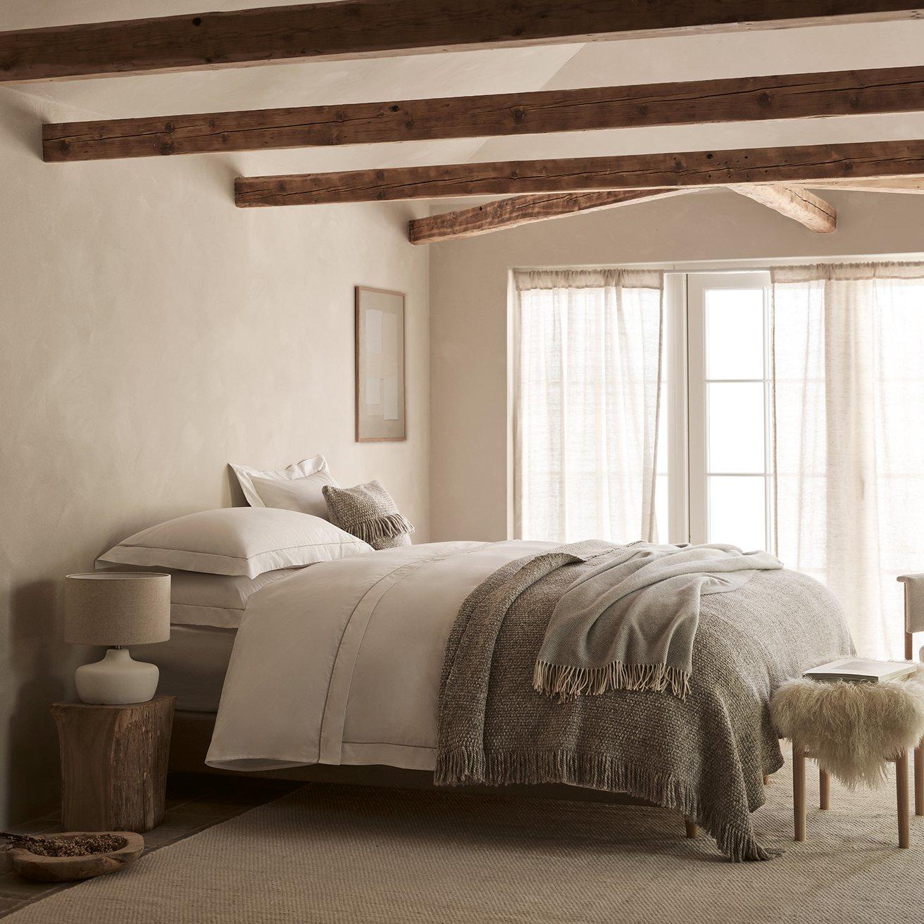 a bedroom with a bed, a chair, a lamp, and a window