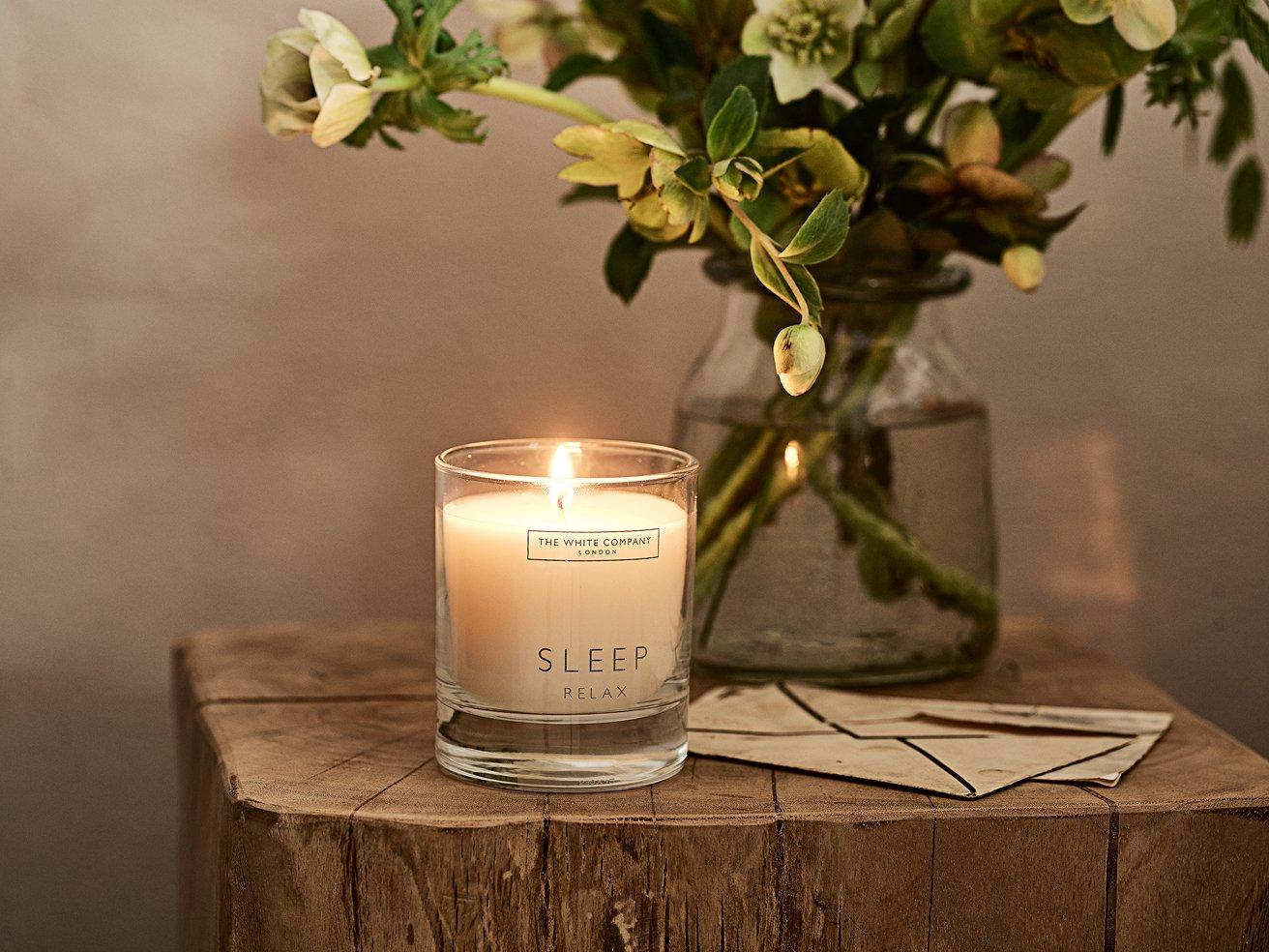 a candle sitting on a wooden table next to a vase of flowers