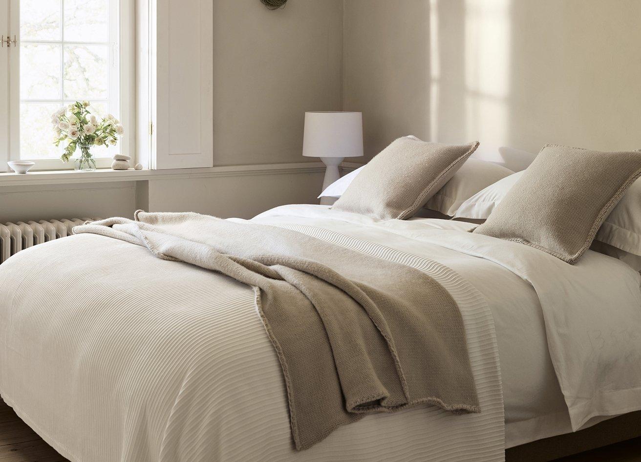 a bed with a white comforter and yellow pillow in a bedroom