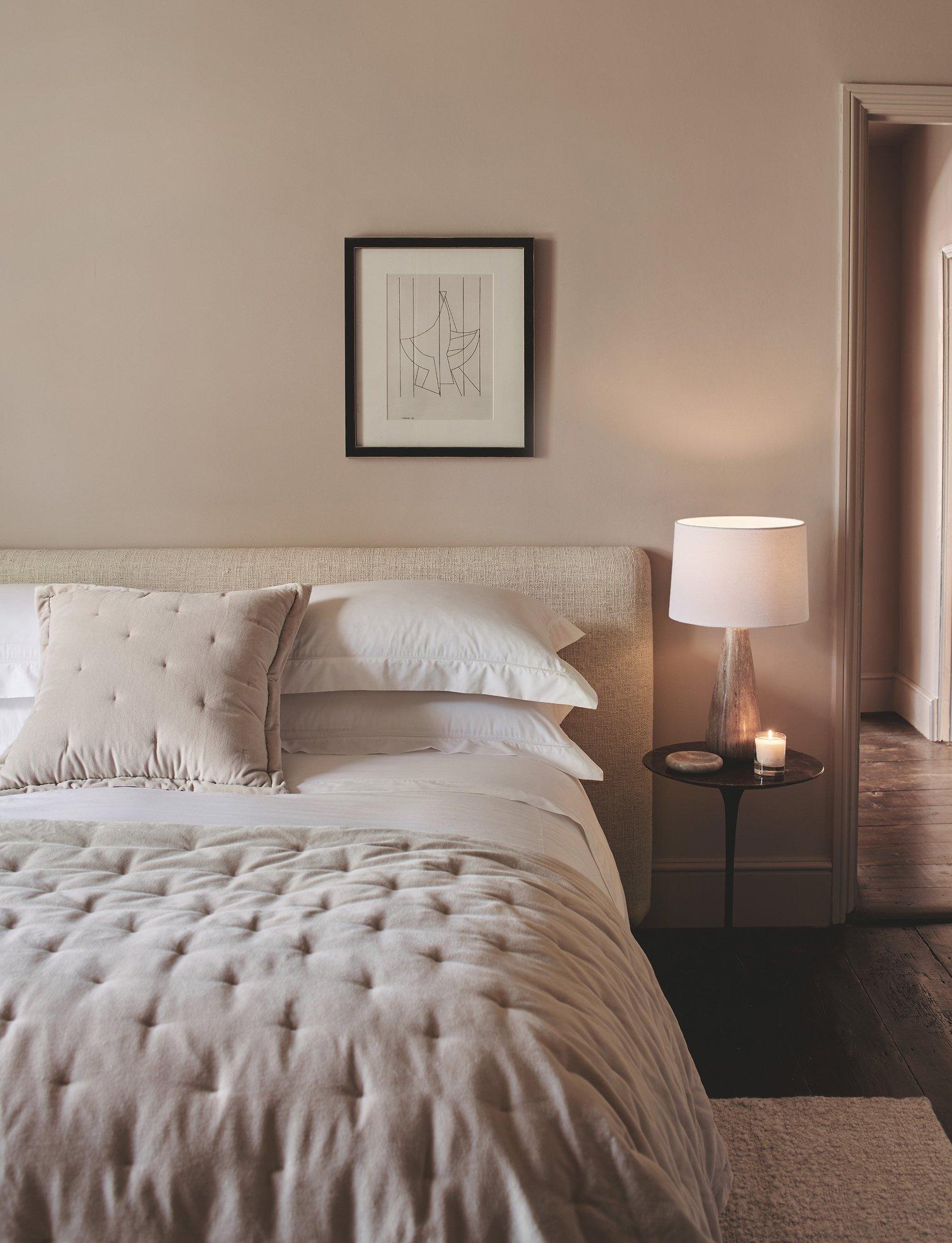 a bedroom with a bed, nightstand, and lamp on a white bed