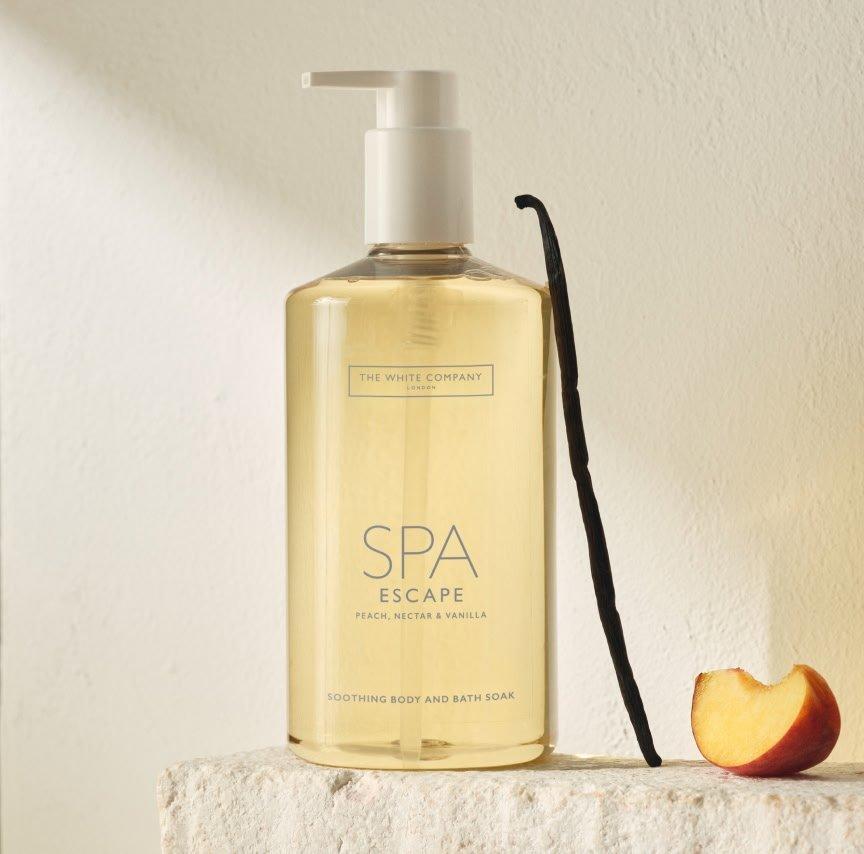 a bottle of spa escape soap sitting on a counter next to an apple
