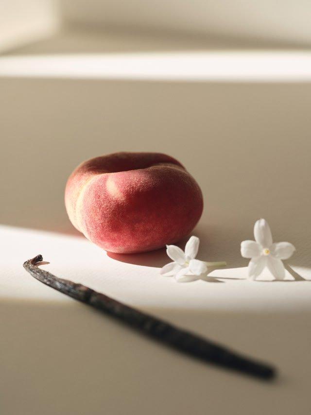 a peach and a vanilla bean on a white surface