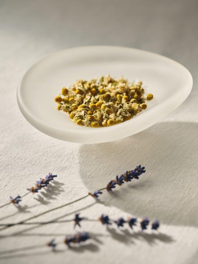 a white plate with dried flowers and a small bowl of seeds