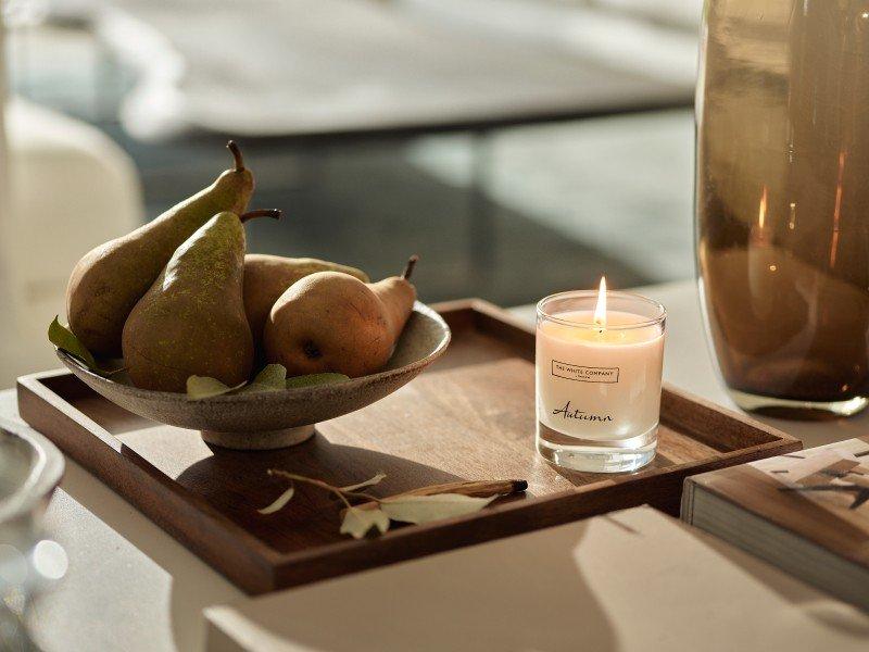 a small table with a candle, vase, and books on it