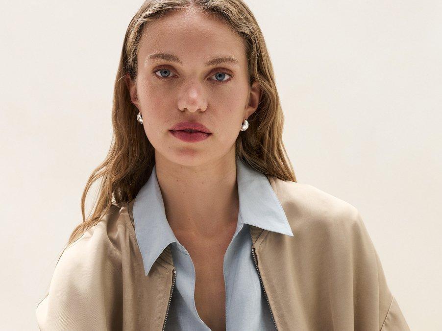 a woman in a beige jacket and blue shirt